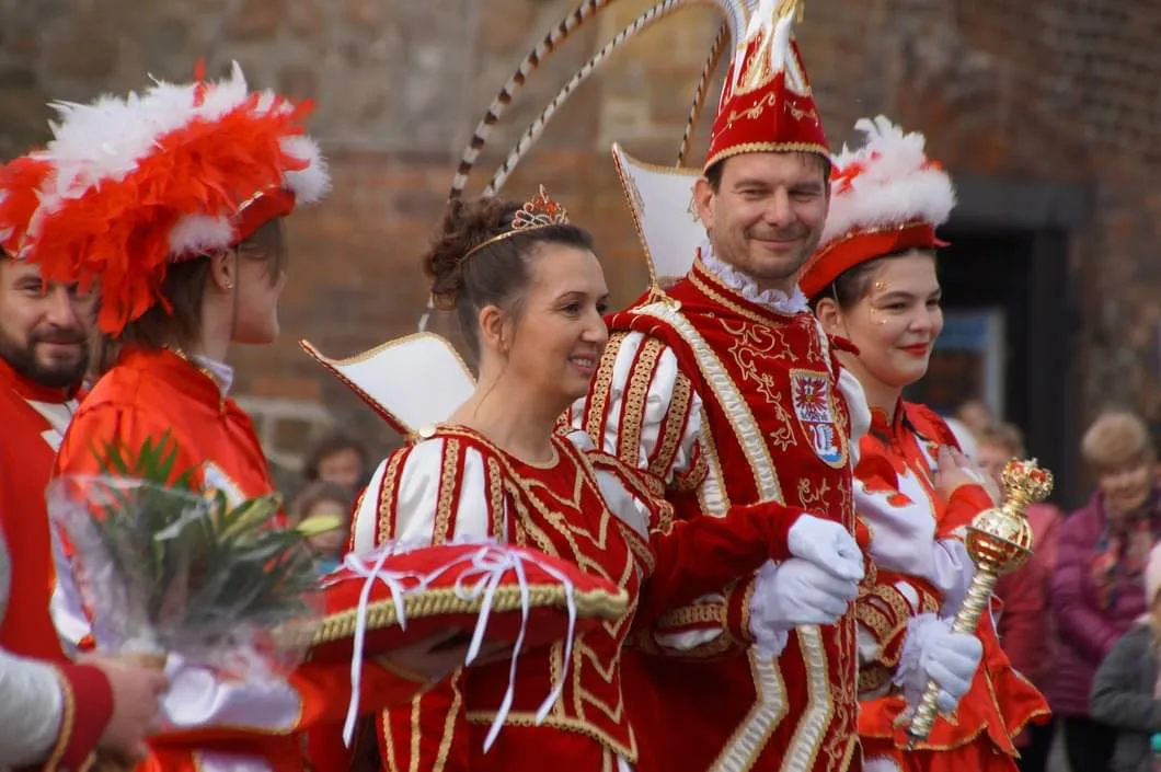 Anja Strebelow und Kai Jackwitz waren das letztjährige Prinzenpaar. Sie wollte schon immer Prinzessin sein – er hingegen musste überredet werden. Man sieht eine Frau und einen Mann in altmodischer, edler Kleidung, umgeben von Kostümierten.